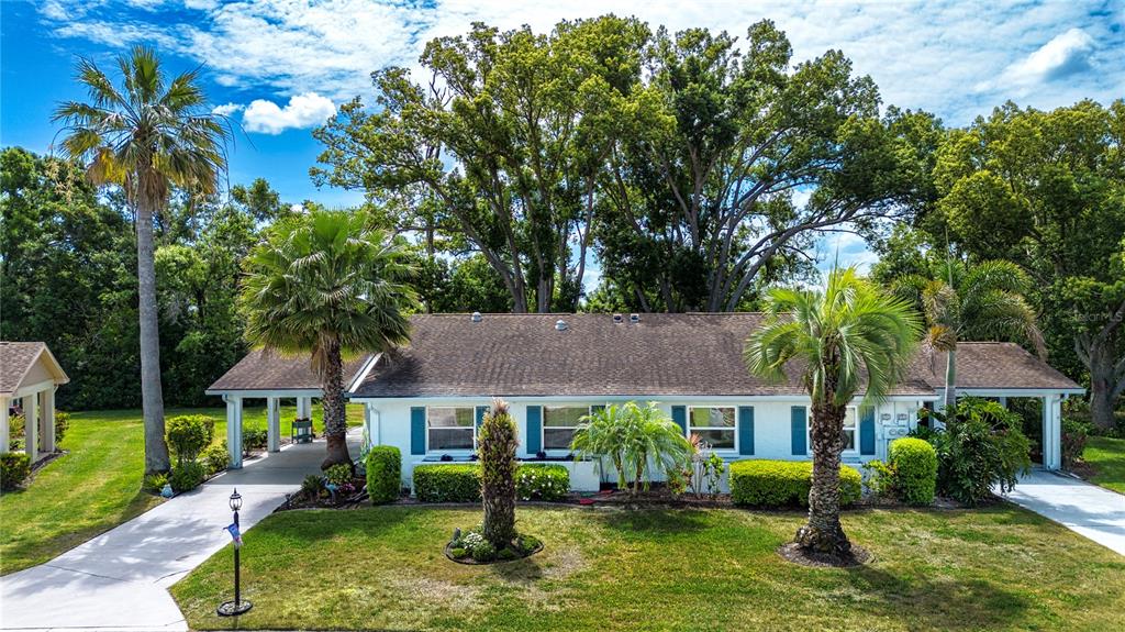 A one-story white house with blue shutters, a brown roof, and two palm trees — 505 FINSBURY CIRCLE UNIT A, SUN CITY CENTER, FL