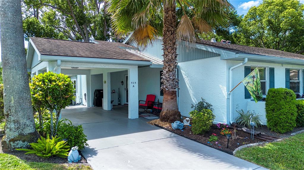 A single-story house features a covered carport, a palm tree, and a small front garden — 505 FINSBURY CIRCLE UNIT A, SUN CITY CENTER, FL