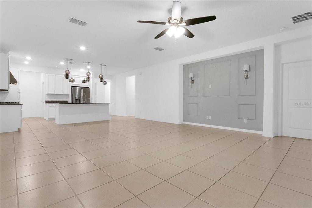 An open-concept living area features light tile flooring, a kitchen island, and a paneled wall — 901 SABAL BREEZE LANE, APOPKA, FL