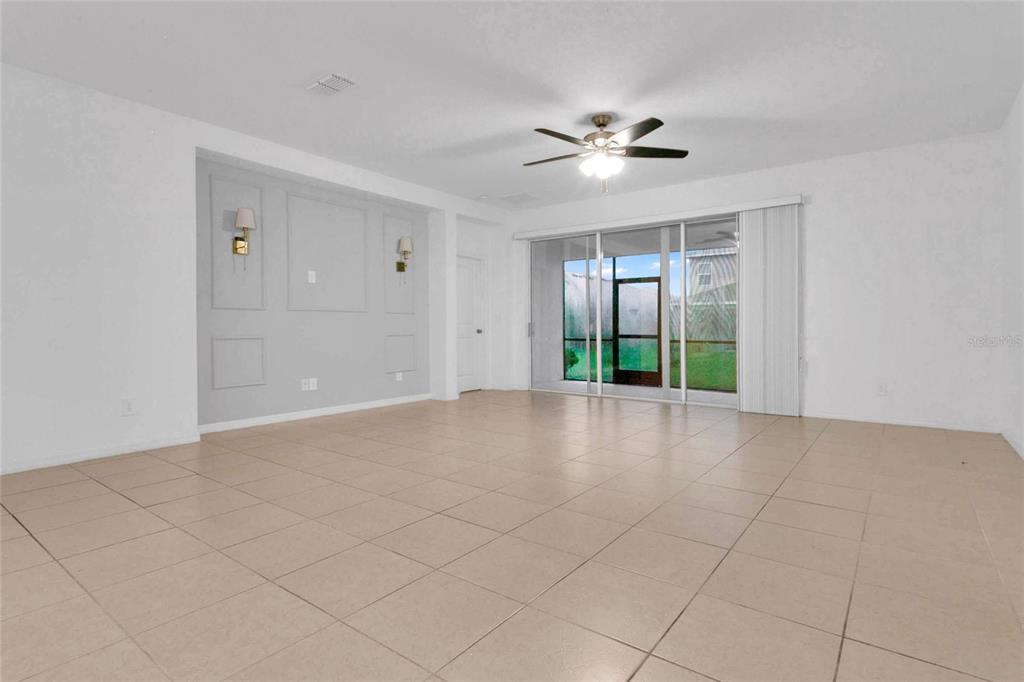 A spacious living room features light tile flooring, a ceiling fan, and a paneled accent wall — 901 SABAL BREEZE LANE, APOPKA, FL