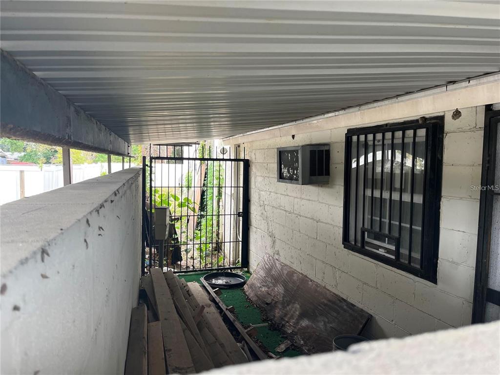 A covered outdoor area features a concrete block wall, a window with bars, and lumber — 3302 E DR MARTIN LUTHER KING JR BOULEVARD, TAMPA, FL