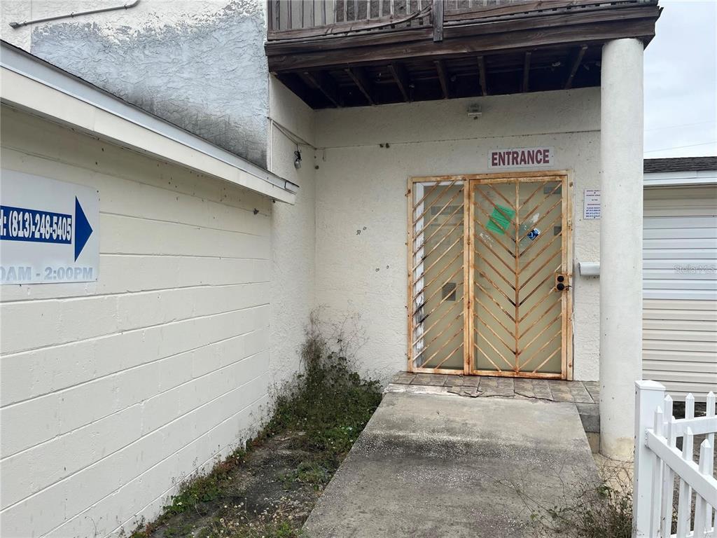 An exterior view of a building entrance with a metal security gate and concrete walkway — 3302 E DR MARTIN LUTHER KING JR BOULEVARD, TAMPA, FL