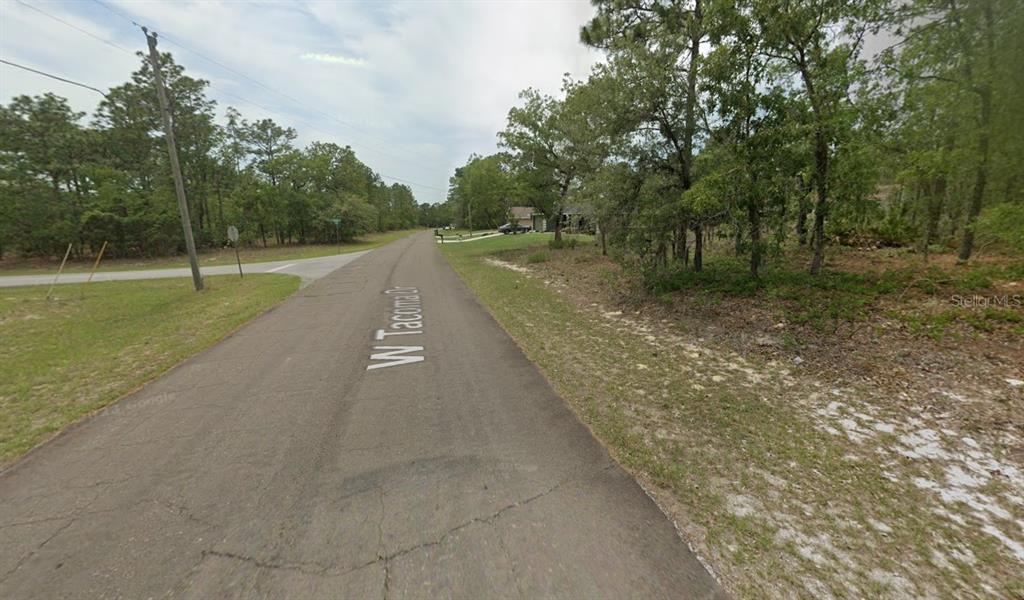 A paved road runs through a wooded area with a house visible in the distance — 2065 W TACOMA DRIVE, CITRUS SPRINGS, FL