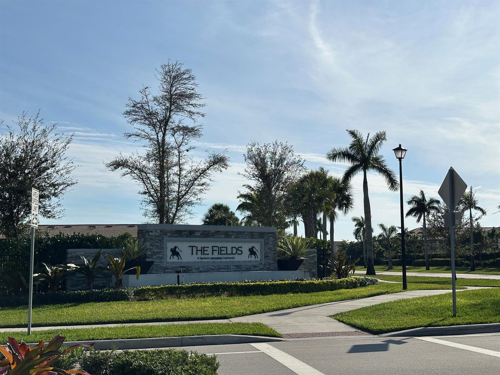 A stone entrance sign for The Fields community stands beside a sidewalk and palm trees — 8191 Cinch Way, Lake Worth FL 33467, LAKE WORTH, FL
