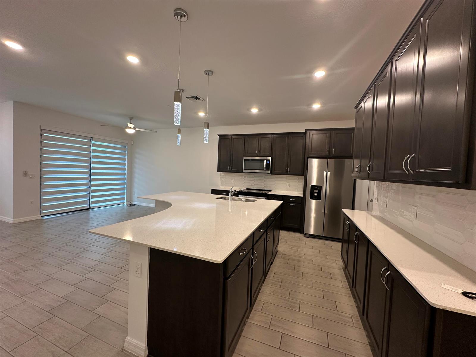 A modern kitchen features dark wood cabinets, white quartz countertops, and stainless steel appliances — 8191 Cinch Way, Lake Worth FL 33467, LAKE WORTH, FL