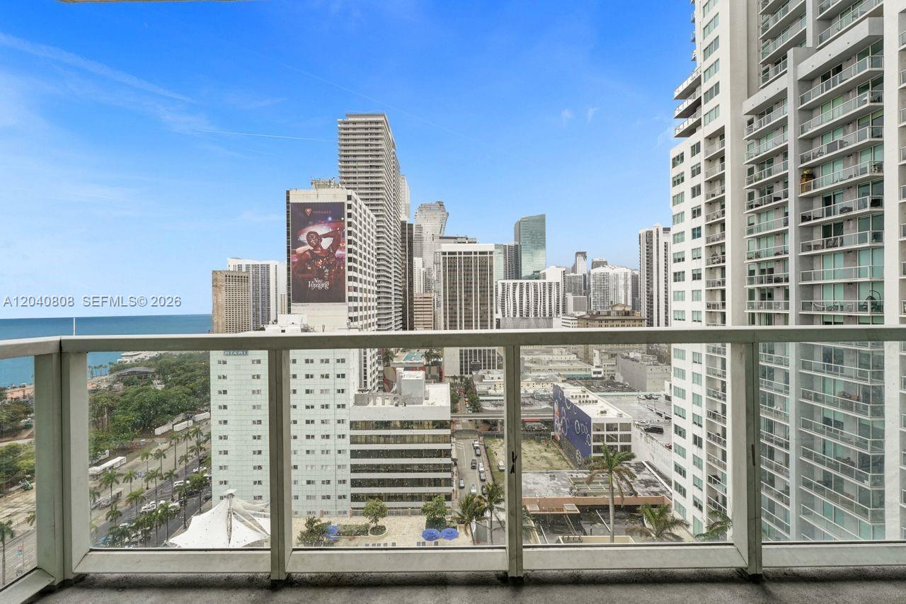 A balcony overlooks a dense urban skyline and the ocean under a clear blue sky — 244 Biscayne Blvd # 2005, Miami FL 33132, MIAMI, FL