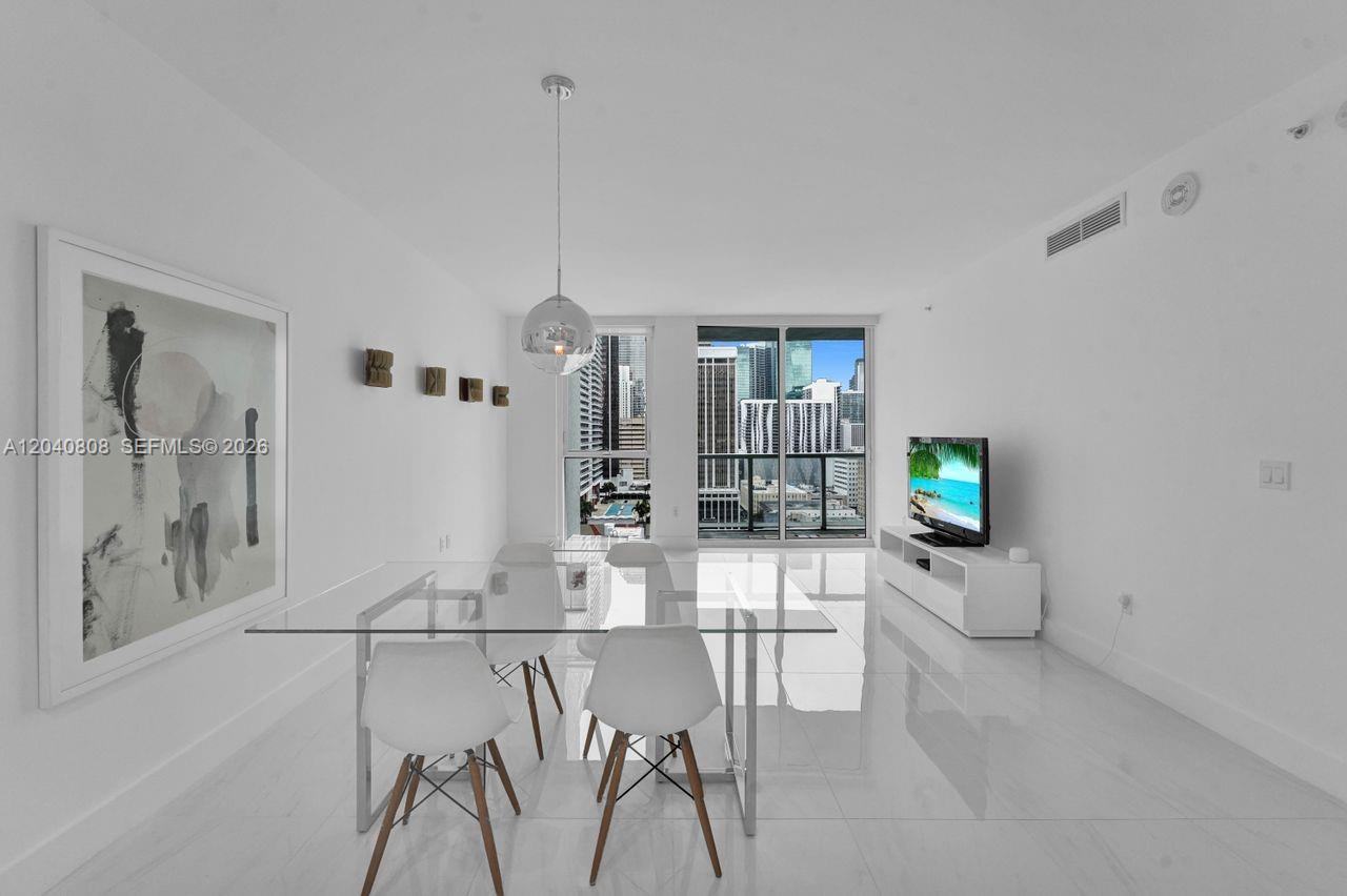 A modern dining room features a glass table, white chairs, and floor-to-ceiling city views — 244 Biscayne Blvd # 2005, Miami FL 33132, MIAMI, FL
