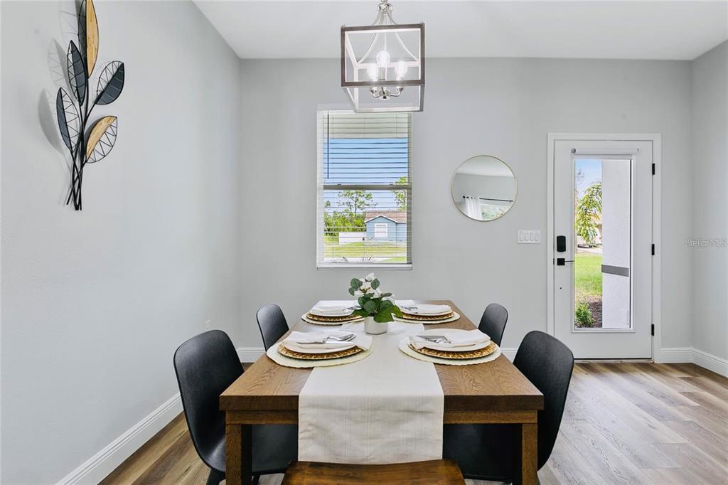 A dining room features a wooden table, black chairs, a light fixture, and a glass door — 16451 STRAUSS AVENUE, PORT CHARLOTTE, FL