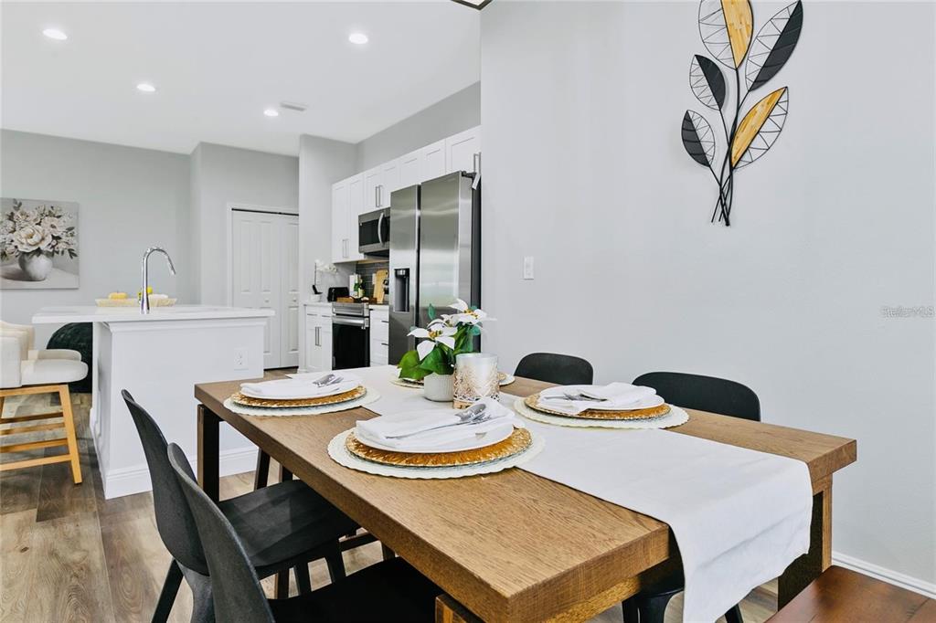 A dining area with a wooden table and chairs sits adjacent to a modern kitchen — 16451 STRAUSS AVENUE, PORT CHARLOTTE, FL