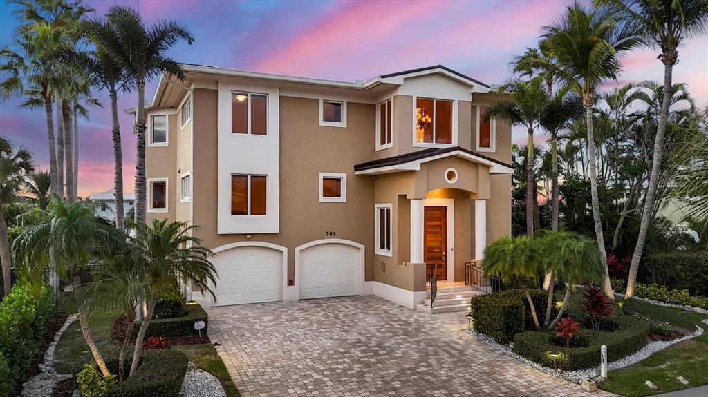 A three-story tan house with a two-car garage and a paved driveway at sunset — 761 NORTON STREET, LONGBOAT KEY, FL