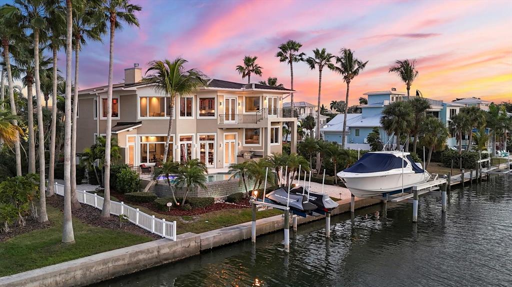 A multi-story waterfront house with a pool, boat lift, and palm trees at sunset — 761 NORTON STREET, LONGBOAT KEY, FL