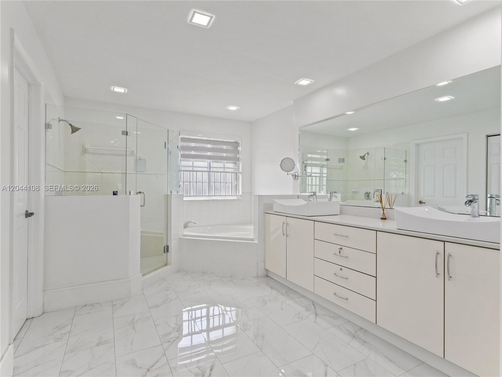 A bright, modern bathroom features a glass-enclosed shower, a soaking tub, and a double vanity — 7086 NW 116th Ct, Doral FL 33178, DORAL, FL