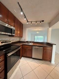 A kitchen features wood cabinets, stainless steel appliances, a track light, and tile flooring — 6552 Arleigh Ct # 102, Boca Raton FL 33433, BOCA RATON, FL