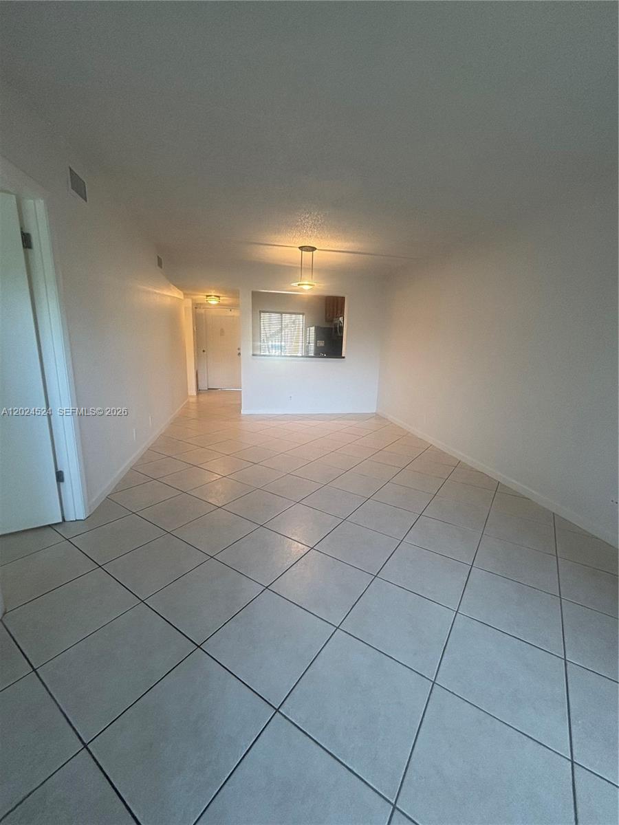 A living area features light-colored diagonal floor tiles, white walls, and a pass-through kitchen window — 6552 Arleigh Ct # 102, Boca Raton FL 33433, BOCA RATON, FL
