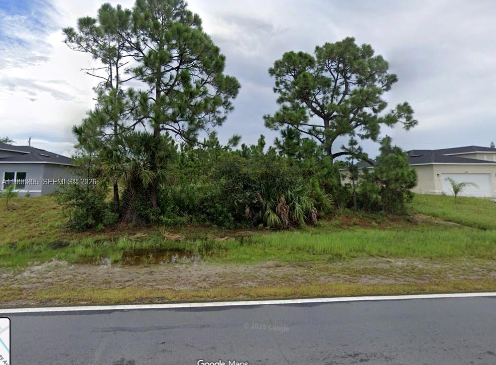A vacant, tree-covered residential lot is situated between two single-family homes — 2065 SE Cogan Dr, Palm Bay FL 32909, PALM BAY, FL