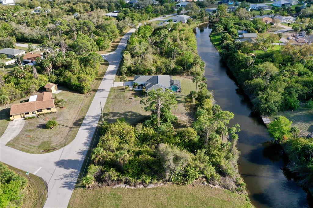 An aerial view shows a house with a pool situated between a road and a canal — 7241 JENNIFER DRIVE, PORT CHARLOTTE, FL