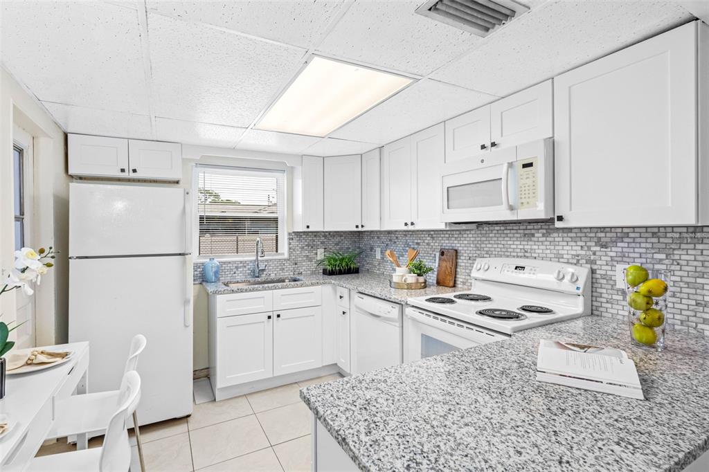 A living room with tile floors and a ceiling fan opens to a white kitchen — 72 LAKE SHORE DRIVE, PALM HARBOR, FL