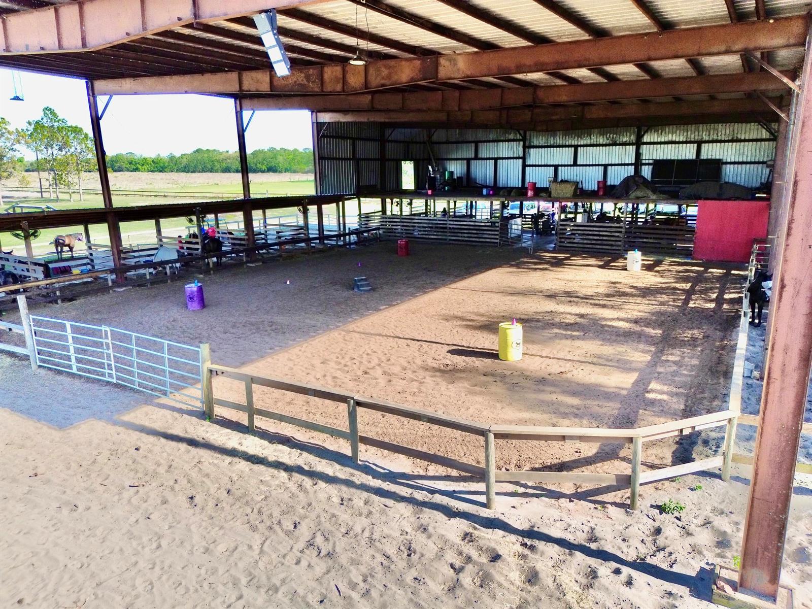 An open-air horse riding arena features a dirt floor, wooden fencing, and metal roofing — 3020 N Bowden Road, FL 33825, FL