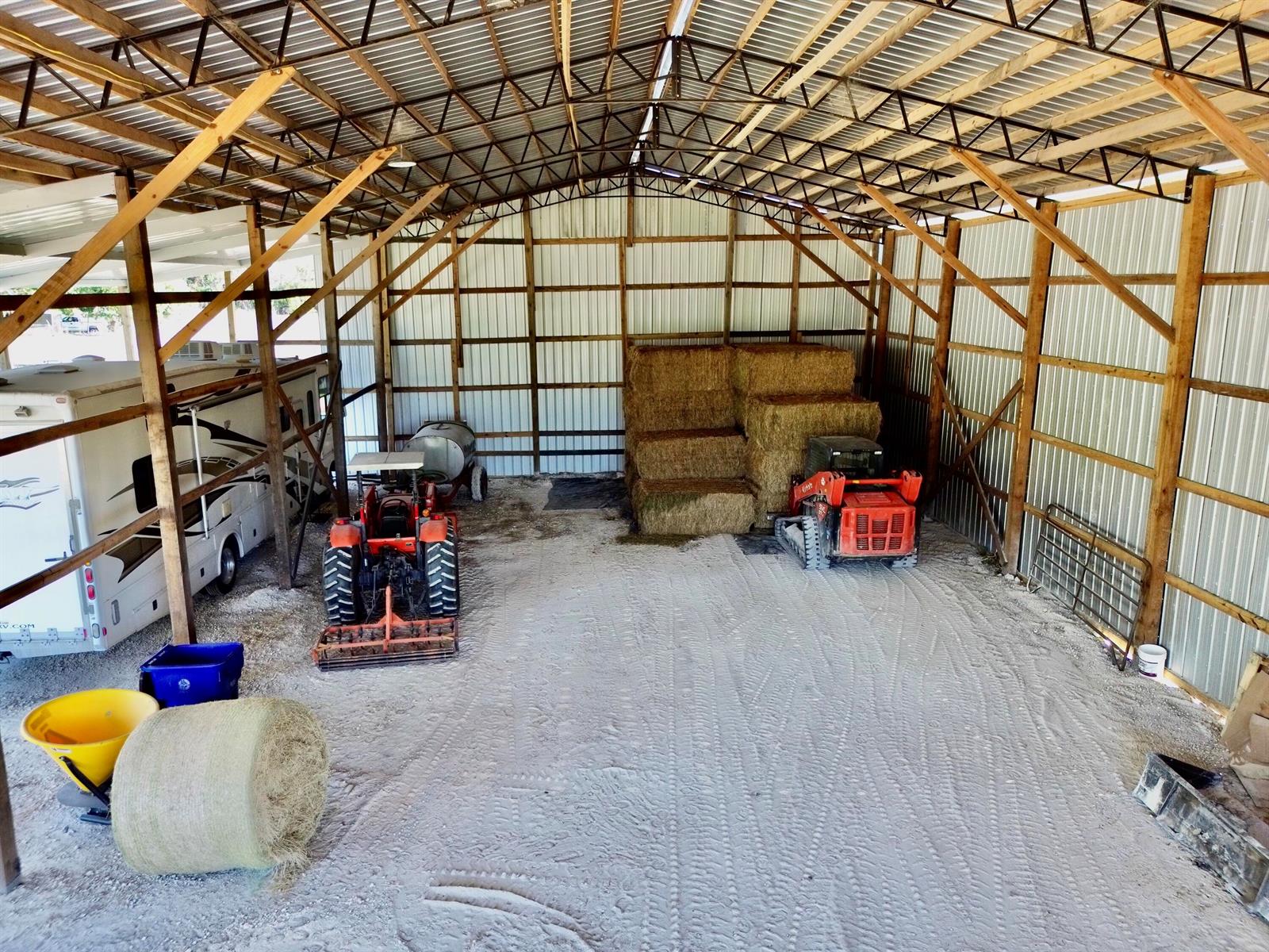 A large metal pole barn houses a tractor, a skid steer, hay bales, and an RV — 3020 N Bowden Road, FL 33825, FL