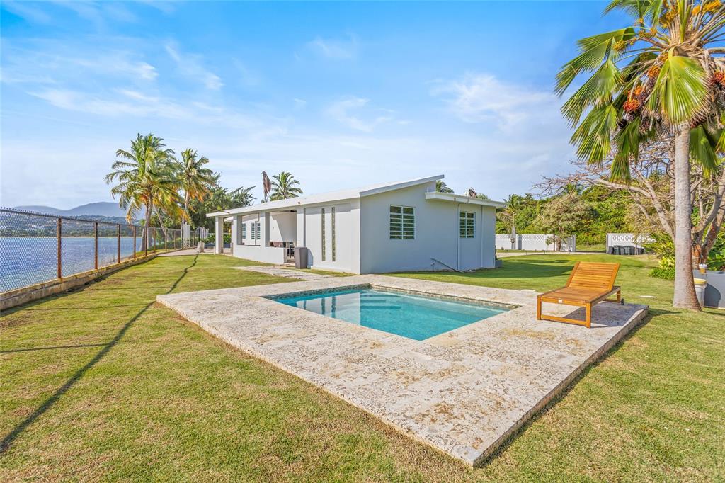 A small swimming pool sits on a stone patio next to a white house — 14-2 CAMINO LAS PICUAS, RIO GRANDE, PR