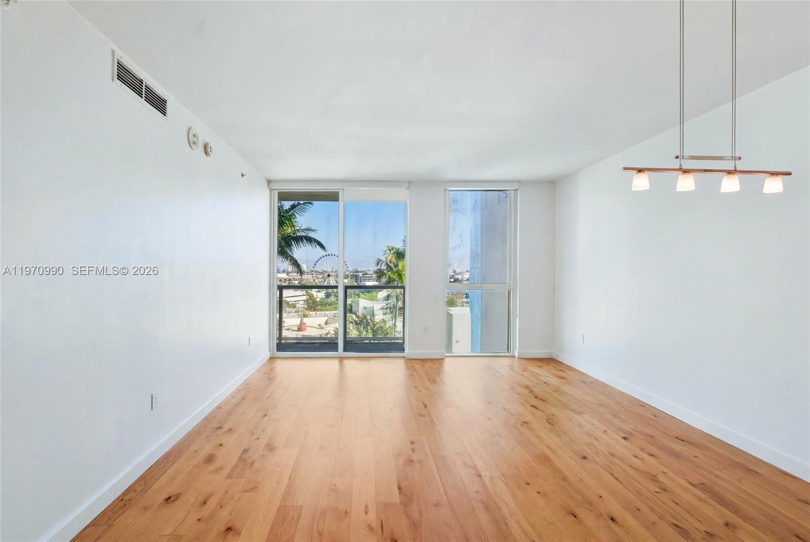 An empty room features light wood flooring, white walls, a modern light fixture, and floor-to-ceiling windows — 253 NE 2nd St # 1007, Miami FL 33132, MIAMI, FL