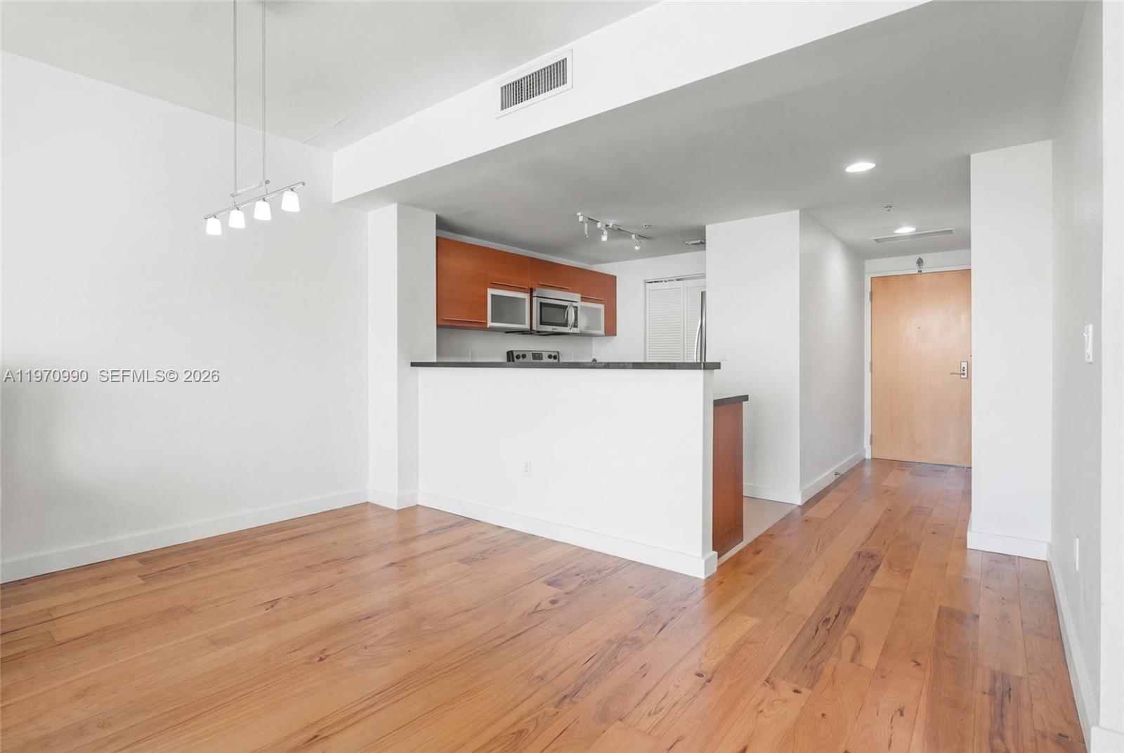 This room features hardwood flooring, a kitchen with wooden cabinets, and a breakfast bar — 253 NE 2nd St # 1007, Miami FL 33132, MIAMI, FL
