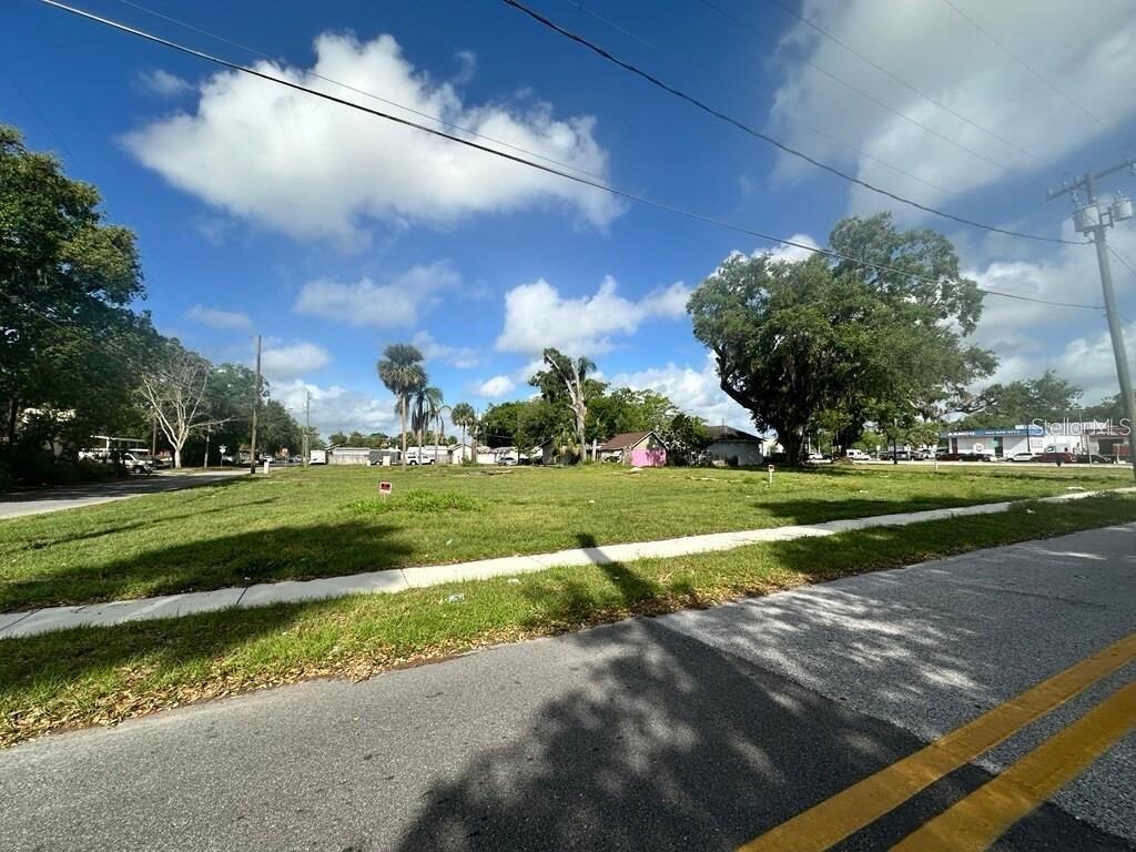 A vacant, grassy corner lot sits along a paved road under a blue sky — 1314 BRACK STREET, KISSIMMEE, FL