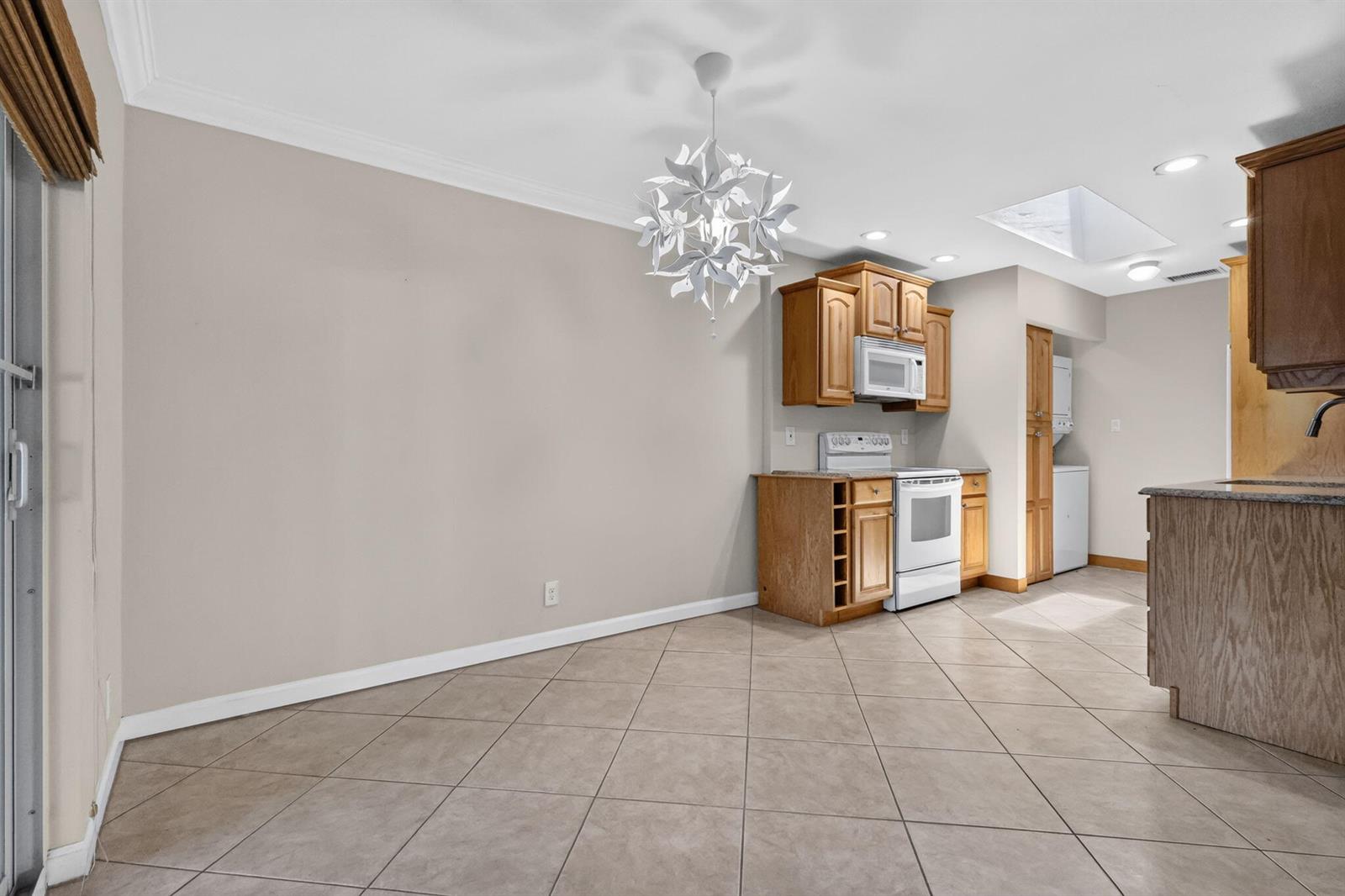 A kitchen and dining area with tile flooring, light-colored walls, and wooden cabinetry — 3358 Christopher Street, West Palm Beach FL 33417, WEST PALM BEACH, FL