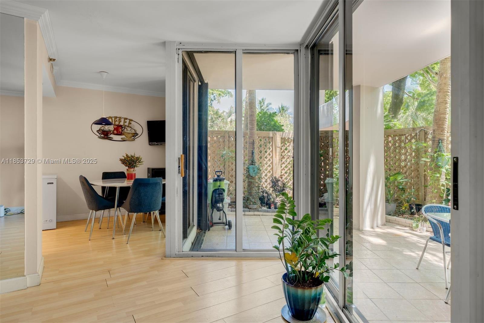 A dining area with light wood floors opens through sliding glass doors to a tiled patio — 2000 Towerside Ter # 308, Miami FL 33138, MIAMI, FL