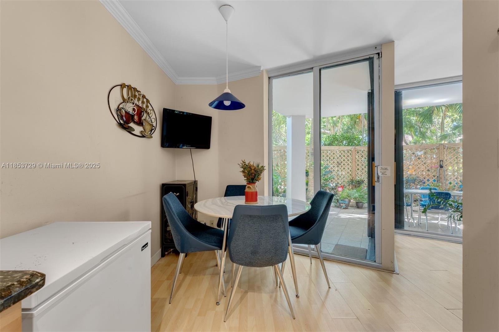 A dining area features a round table, four blue chairs, and a sliding glass door — 2000 Towerside Ter # 308, Miami FL 33138, MIAMI, FL