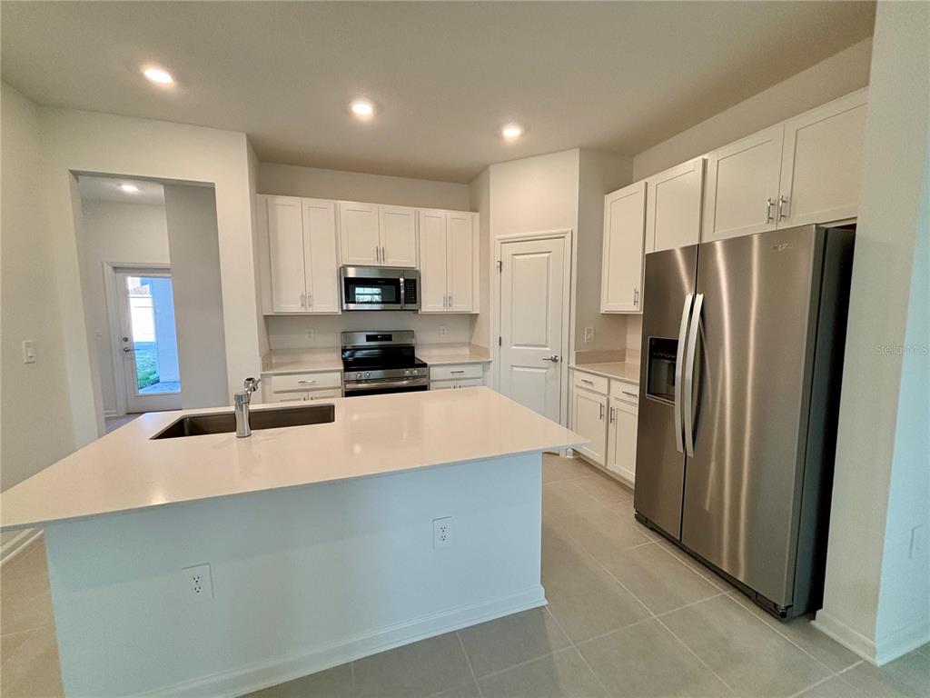 A modern kitchen features white cabinets, stainless steel appliances, and a large central island — 5770 MEDITATION DRIVE, CLERMONT, FL