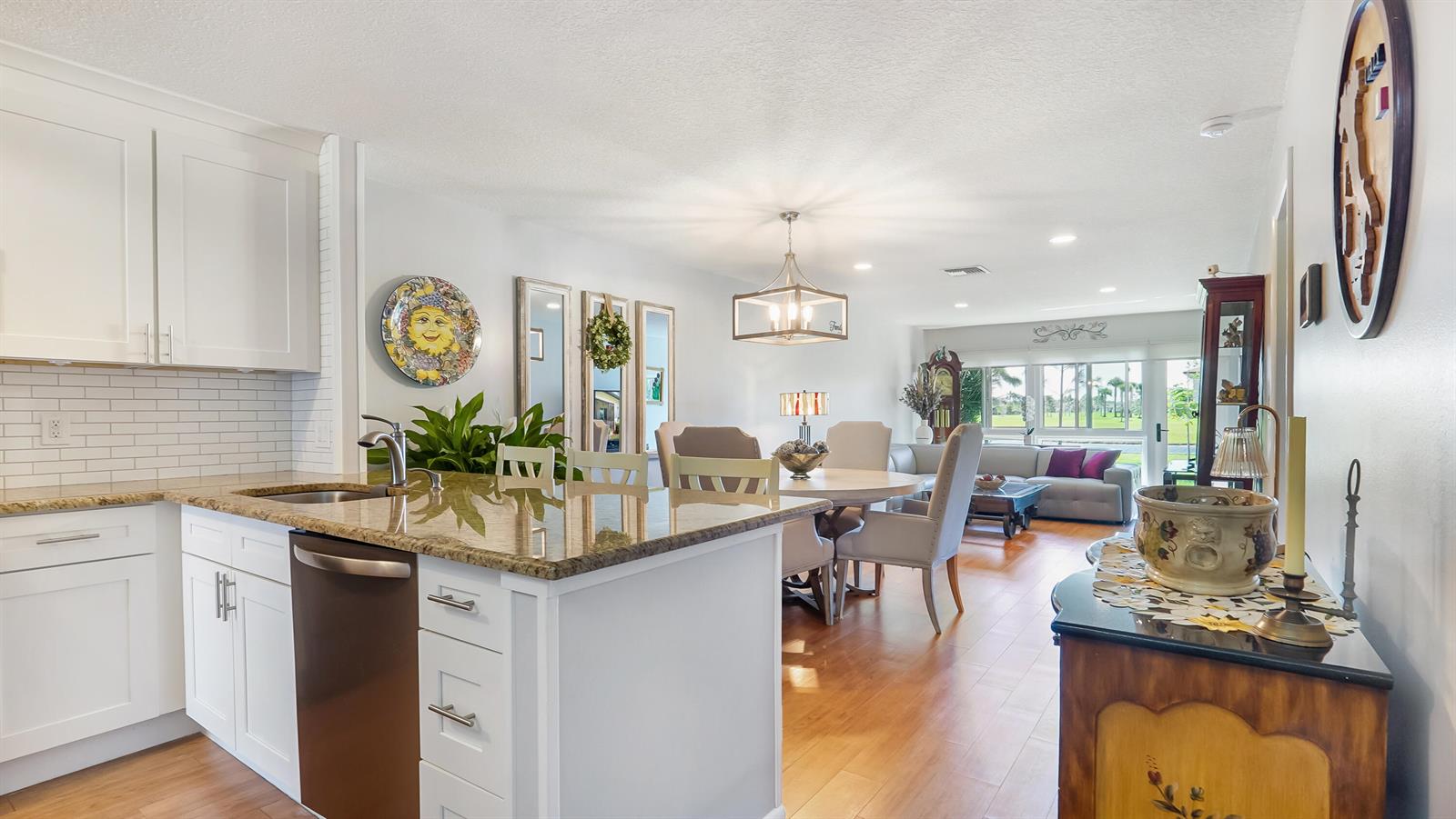 A kitchen with white cabinets and granite countertops opens into a dining and living area — 5620 Queen Palm Court # C, Delray Beach FL 33484, DELRAY BEACH, FL