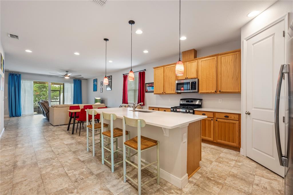 A kitchen with light wood cabinets, a white island with bar stools, and tiled floors — 390 CASA VERANO LANE, DAVENPORT, FL