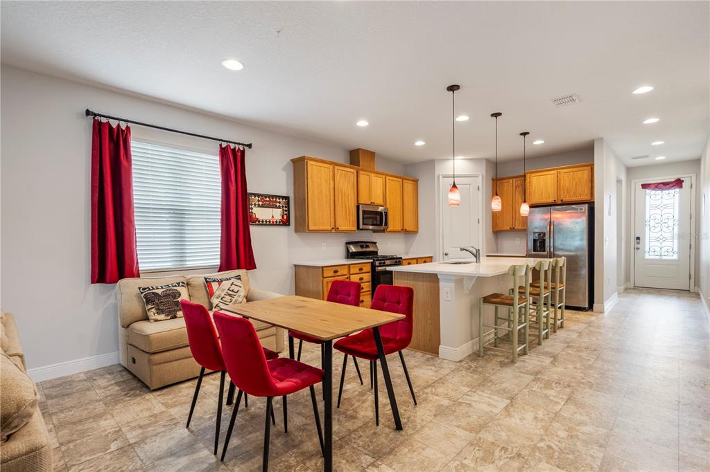 A kitchen and dining area features light wood cabinets, a central island, and red chairs — 390 CASA VERANO LANE, DAVENPORT, FL