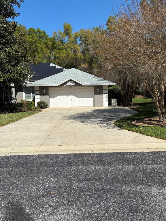 A single-story house with a white garage door, gray siding, and a light-colored shingled roof — 19433 SW 82ND PLACE ROAD, DUNNELLON, FL