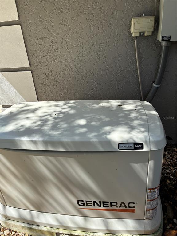 A Generac Guardian 24kW standby generator sits on a concrete pad against a stucco wall — 19433 SW 82ND PLACE ROAD, DUNNELLON, FL