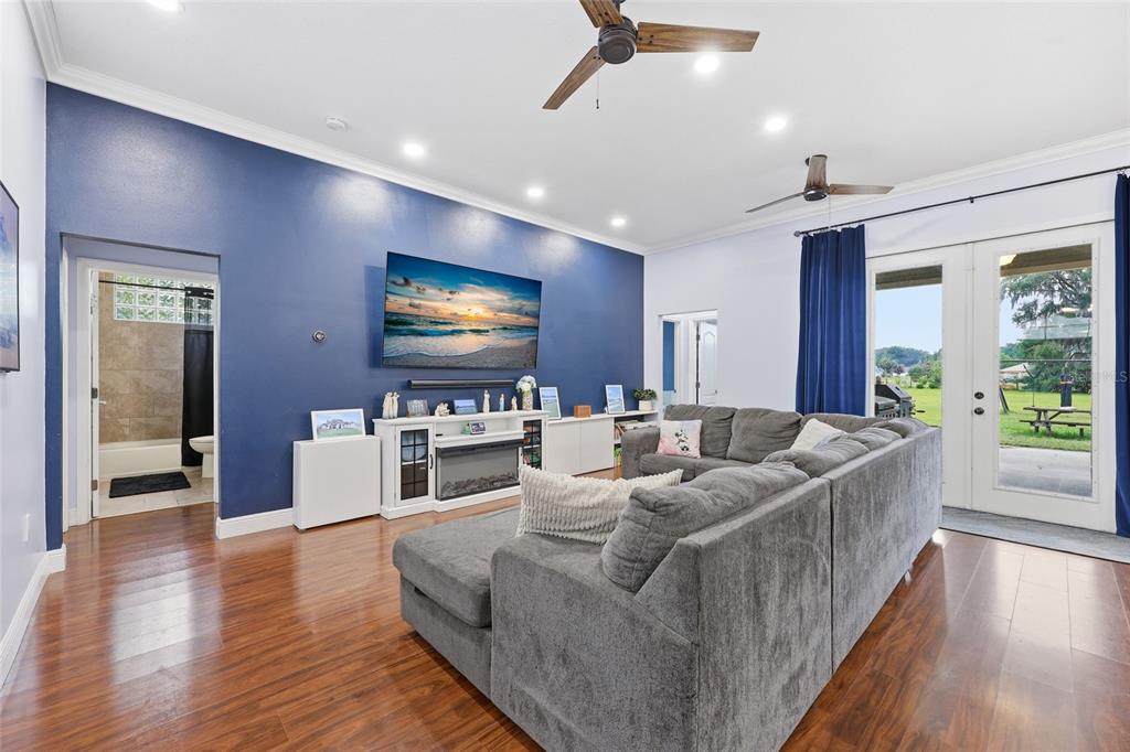 A living room with a blue accent wall, gray sectional sofa, and wood flooring — 25672 NW 173RD AVENUE, HIGH SPRINGS, FL