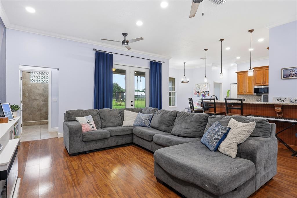 A living room features a large gray sectional sofa, a blue accent wall, and wood flooring — 25672 NW 173RD AVENUE, HIGH SPRINGS, FL