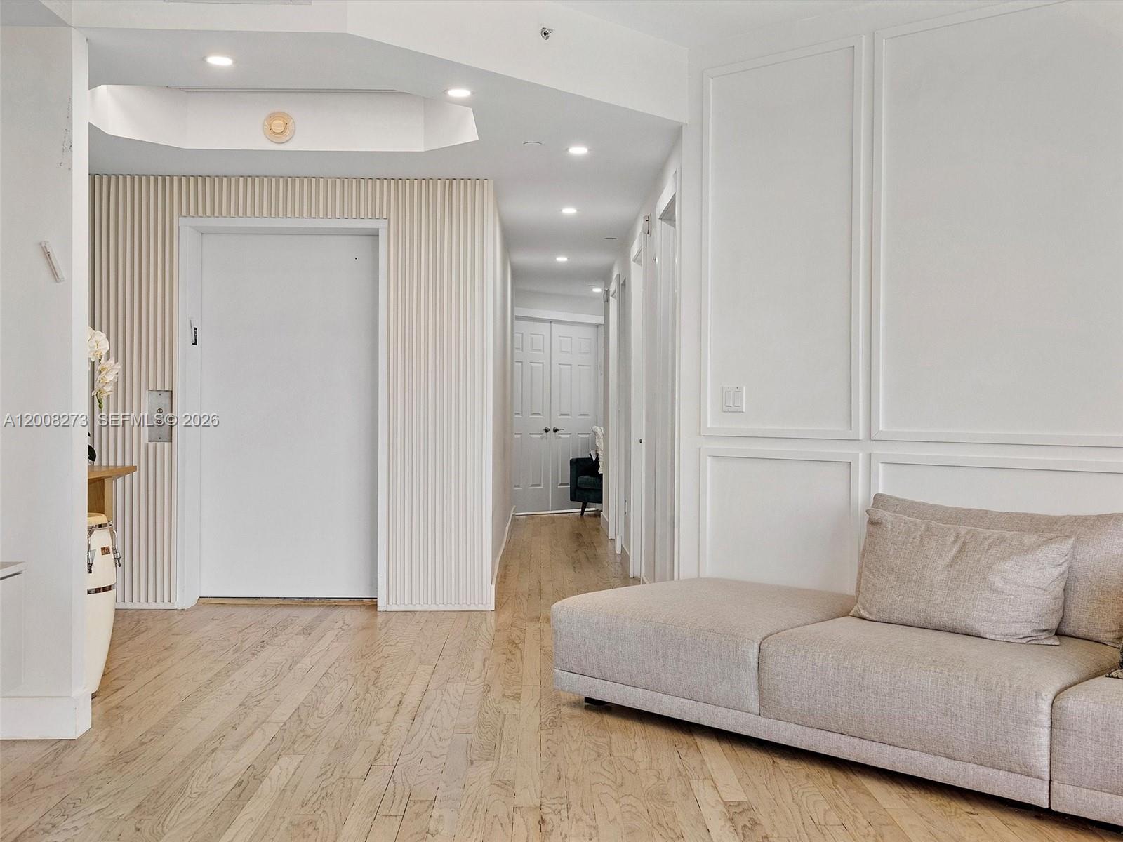 A hallway features light wood flooring, a white door with vertical paneling, and a sofa — 9751 E Bay Harbor Dr # 11A, Bay Harbor Islands FL 33154, BAY HARBOR ISLANDS, FL