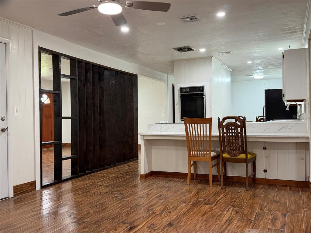 A kitchen with a breakfast bar, wood-look tile flooring, and a dark wood slat wall — 16726 NW COUNTY ROAD 235A, ALACHUA, FL