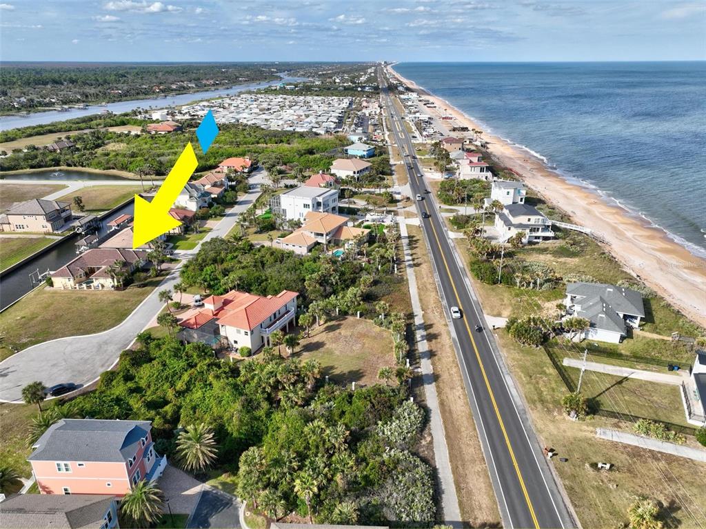 An aerial view shows a coastal neighborhood with houses, a road, and the ocean — 88 HIDDEN COVE, FLAGLER BEACH, FL
