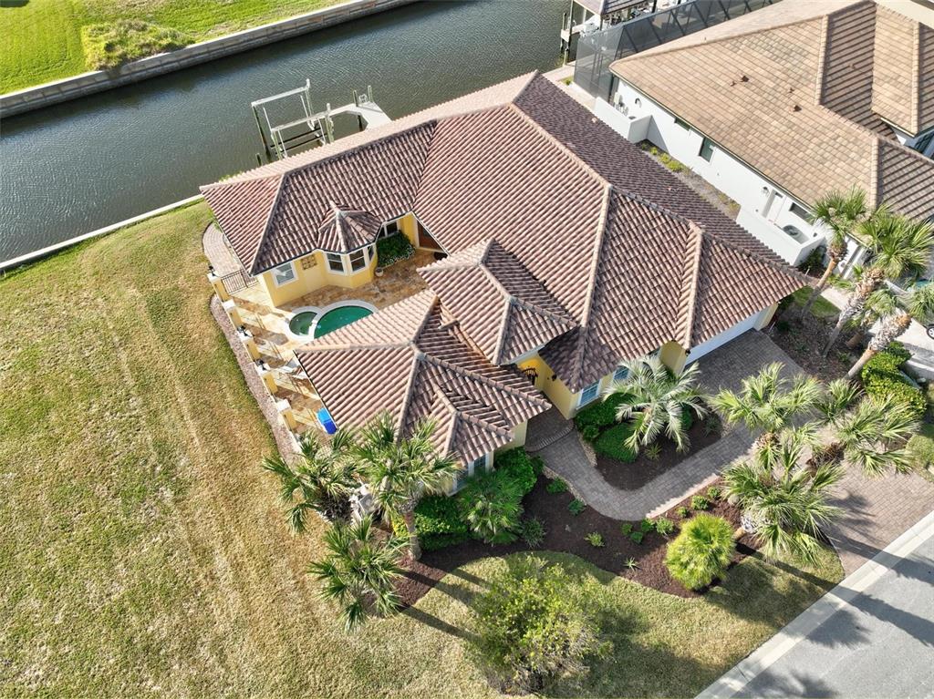 An aerial view shows a yellow house with a tiled roof, pool, and canal access — 88 HIDDEN COVE, FLAGLER BEACH, FL