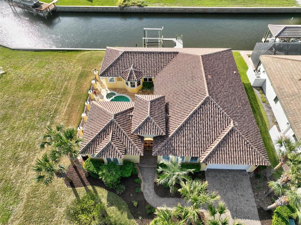 An aerial view shows a yellow house with a tiled roof, pool, and canal access — 88 HIDDEN COVE, FLAGLER BEACH, FL