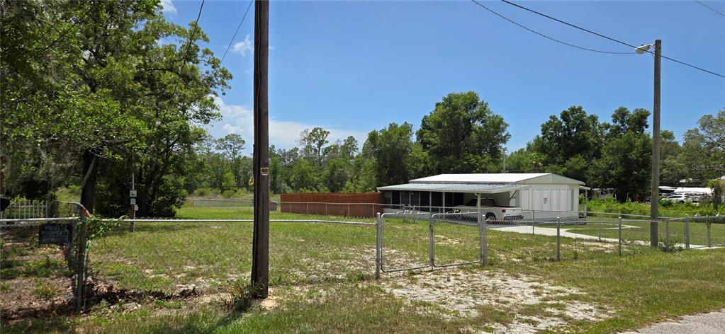 A fenced residential lot features a single-story home with a large attached carport — 0 LAKE DRIVE, WEEKI WACHEE, FL