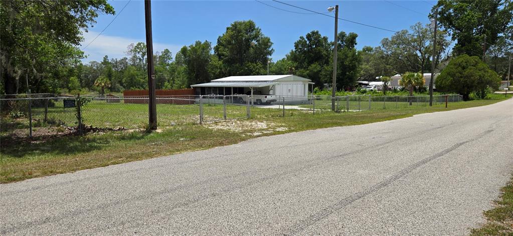 A single-story house with a carport sits behind a chain-link fence on a grassy lot — 0 LAKE DRIVE, WEEKI WACHEE, FL