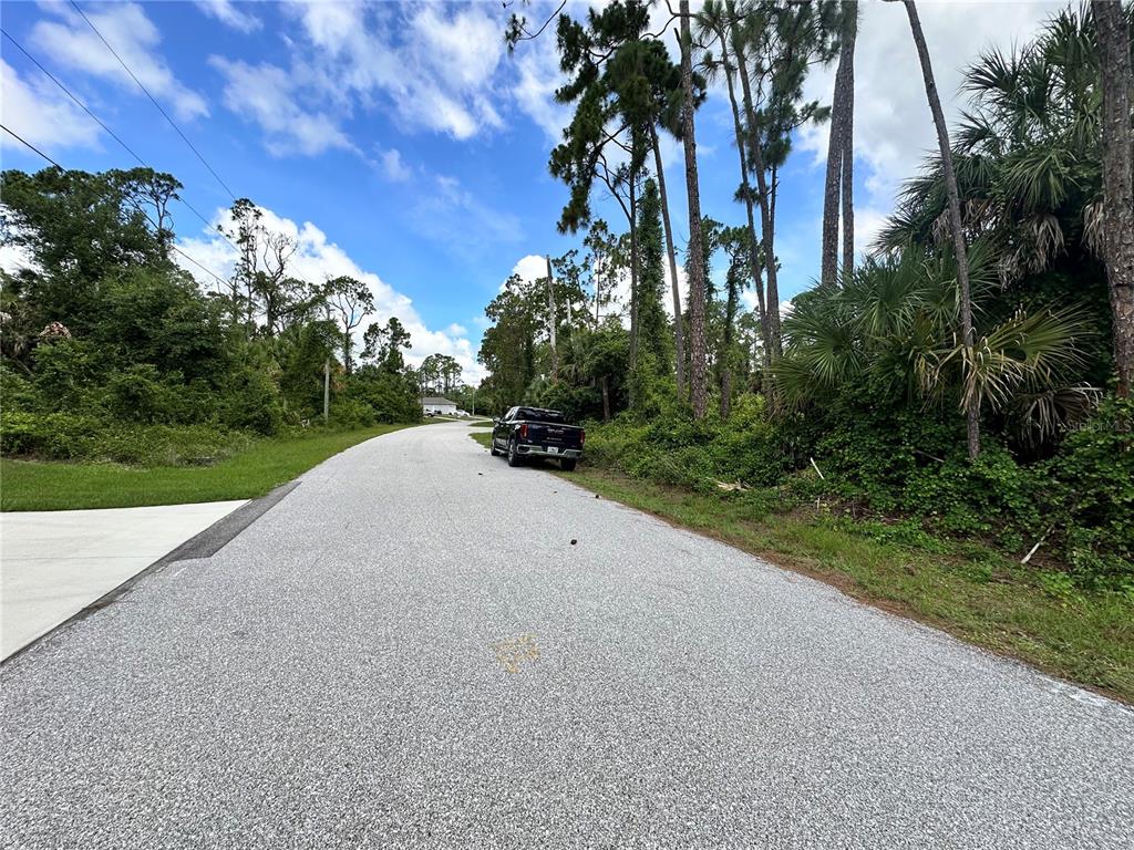 A dark pickup truck is parked on the side of a paved residential road — RUFUS ROAD, NORTH PORT, FL