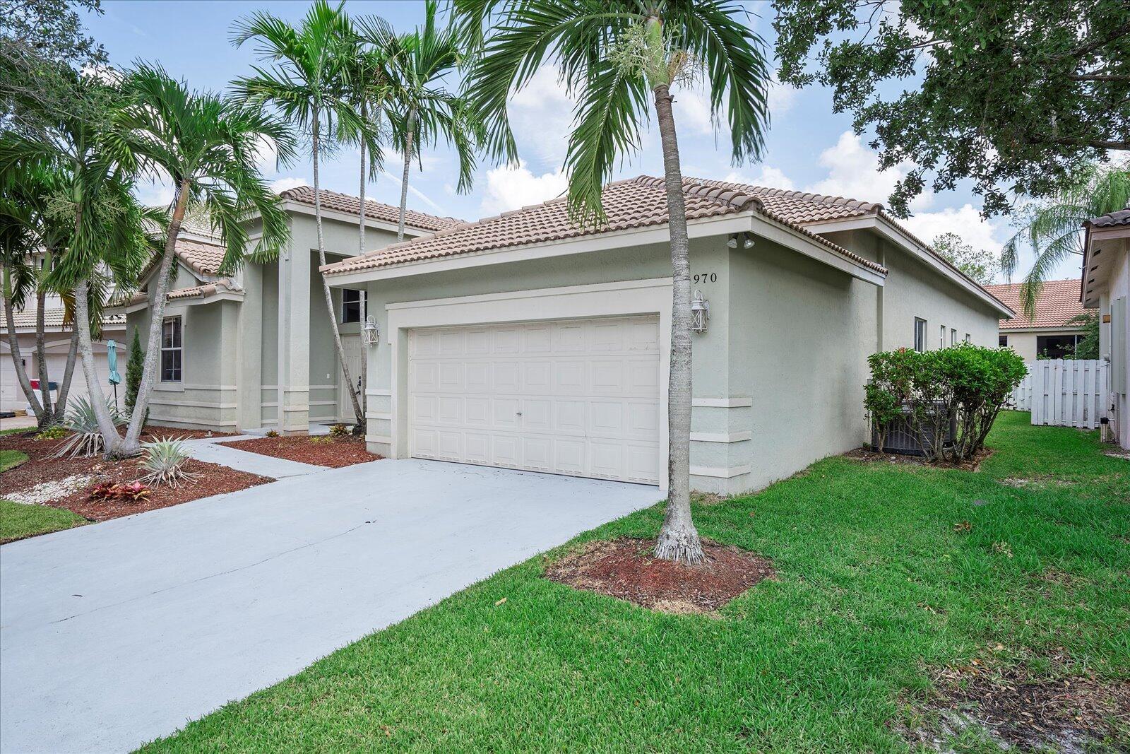 A single-story house with a beige stucco exterior, a two-car garage, and palm trees — 970 Greenwood Road, Weston FL 33327, WESTON, FL