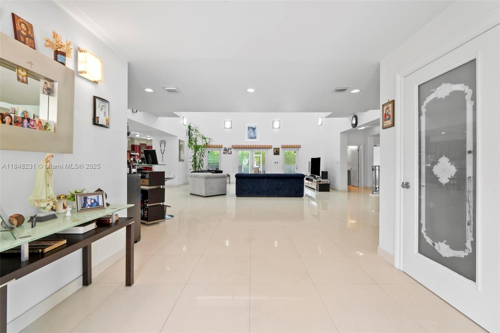 A spacious living room features white tile floors, high ceilings, and a dark blue sofa — 5045 SW 67th Ave, South Miami FL 33155, SOUTH MIAMI, FL