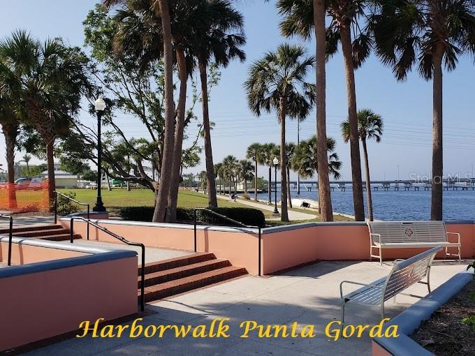 A paved walkway with benches and palm trees overlooks a body of water and bridge — ORTIZ BOULEVARD, NORTH PORT, FL