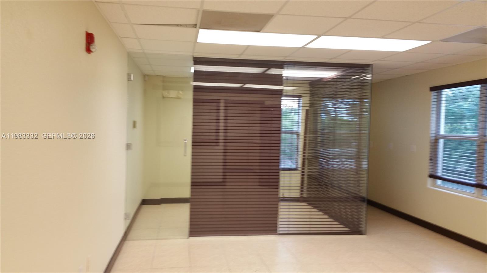 An office space features a glass-walled partition with horizontal blinds and a drop ceiling — 11980 SW 144th Ct # 206, Miami FL 33186, MIAMI, FL